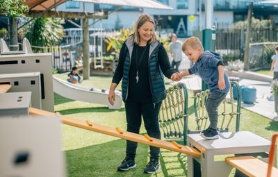 Woman holding a childs hand in a playground